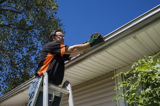 gutter repairman inspecting a damaged downspout in Allston